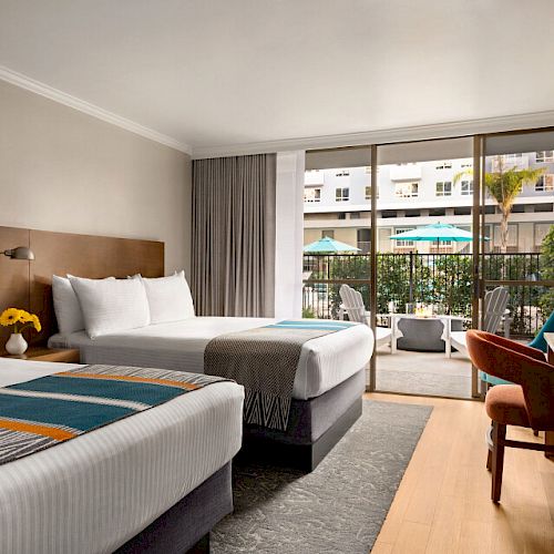 The image shows a hotel room with two beds, a TV, a desk, and a sliding door leading to a balcony with outdoor seating and a pool view.