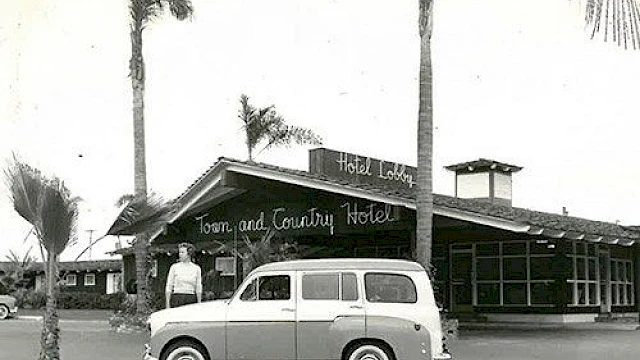 A vintage photo shows a person and classic car in front of the Town and Country Hotel, surrounded by palm trees.